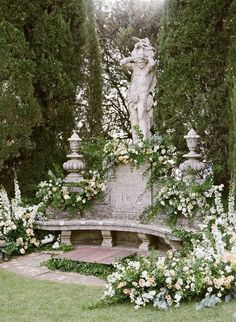 a statue in the middle of a garden surrounded by flowers