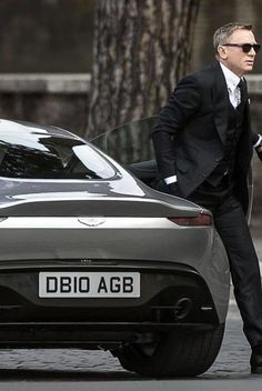 a man in a suit and sunglasses stepping out of a car