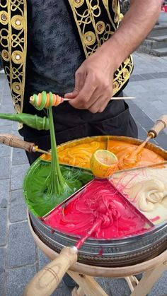 a man is making colorful food on the street