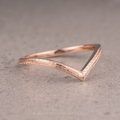 a close up of a gold ring on a gray surface with an arrow shaped design