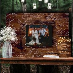 a wooden table topped with a vase filled with flowers next to a couple's photo