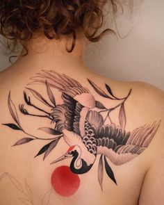 a woman's back with a bird and cherry tattoo on it