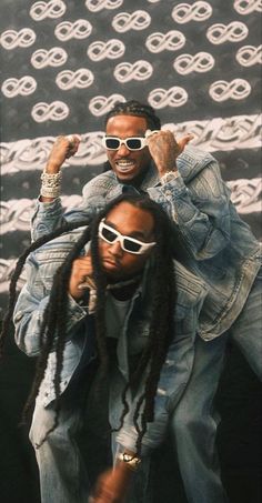 two men with dreadlocks are posing for the camera and one is wearing sunglasses