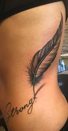 a woman's stomach with a tattoo that reads strong and a feather on it