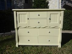 a yellow dresser sitting in the grass next to a house