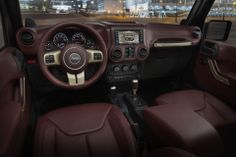 the interior of a jeep with red leather seats and steering wheel, in front of a cityscape