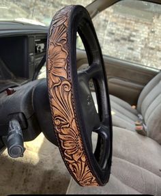 the inside of a car with an intricate leather steering wheel cover