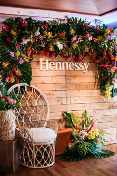 a wooden wall with flowers on it and a white chair in front of the sign that says hennesy