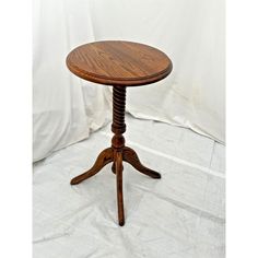 a small wooden table on a white cloth covered floor with a white backdrop in the background