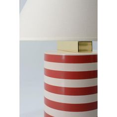 a red and white striped lamp with a gold square on the top, sitting on a table