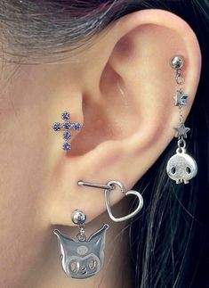 a woman wearing ear piercings with an owl and cross on it