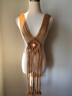 a white mannequin with gold chains on it's back and fringes around the neck