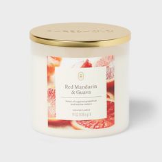 a white candle with red mandarin and guavaa on it