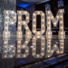 the letters prom and show are lit up in front of a mirrored surface with lights