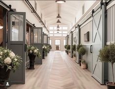 the inside of a horse stable with several stalls and flowers in vases on the floor