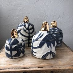 three blue and white ceramic containers sitting on top of a wooden table