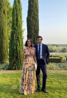 a man and woman standing next to each other in front of trees