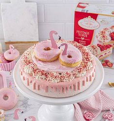 a cake with pink frosting and two donuts on top that are shaped like swans