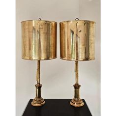 pair of brass lamps on black table with white background