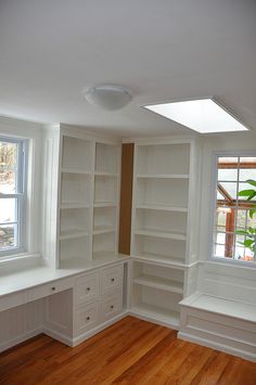 an empty room with white bookcases and wood flooring in the middle of it