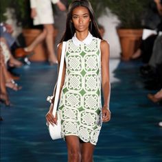 a model walks down the runway wearing a green and white dress with an openwork design