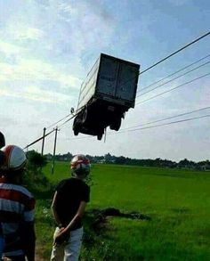 two people watching something in the air on top of a truck that is flying over them