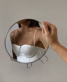 a woman's hand is holding up a mirror to show her bra on the mannequin