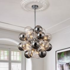 a chandelier hanging from the ceiling in a living room with white walls and windows