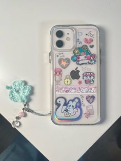 an iphone case with various stickers on it next to a keychain and lanyard