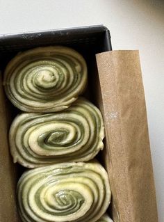 four doughnuts in a brown box with green swirl designs on the top and bottom