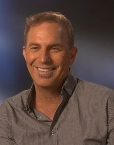 a close up of a person wearing a shirt and smiling at the camera with blue lights behind him