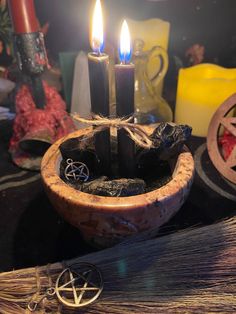 two candles in a wooden bowl on a table with other items and decorations around it