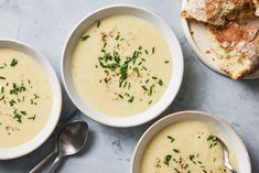 three bowls filled with soup next to bread