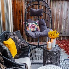 a chair and table on a patio with flowers in the vases next to it