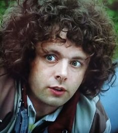 a close up of a person with curly hair and blue eyes looking at the camera