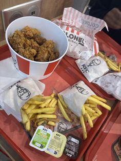 two trays filled with fries and chicken next to a cup of coleslaw