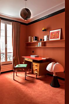 an orange room with two chairs and a desk in front of a large open window