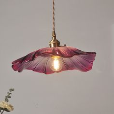 a pink flower is hanging from a light fixture