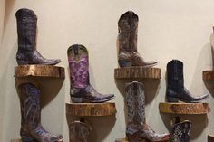 cowboy boots are lined up on wooden shelves