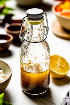 a glass bottle filled with liquid sitting on top of a table next to bowls of vegetables