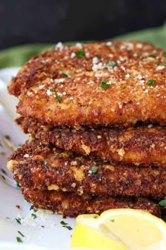 three fried crab cakes on a plate with lemon wedges