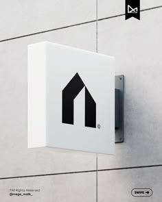 a white sign mounted to the side of a wall with a black arrow on it