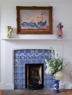 a fireplace with a painting above it and vases in front of the fire place