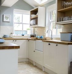 a kitchen filled with lots of white cabinets and counter top space under a skylight