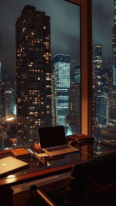 a laptop computer sitting on top of a wooden desk in front of a large window