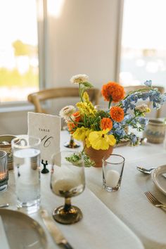 the table is set with flowers, candles and place cards for guests to sit at