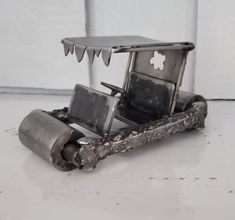 an old metal toy car sitting on top of a white floor next to a wall