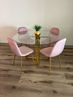 a glass table with four pink chairs around it