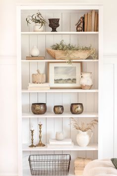 a white book shelf filled with vases and other items