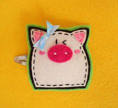 a felt pig with a blue bow on its head is sitting on a yellow surface